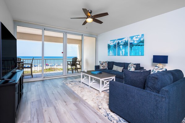A spacious living area with a balcony overlooking the beach, a ceiling fan, and artwork on the wall. - Regency 308 -NEW LISTING AS OF AUGUST 2026! Sea You on the Flip Tide! (Navarre)