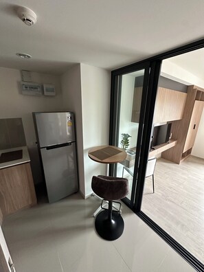 A modern kitchen with a refrigerator, a small dining table, and a chair. - Hua Hin La Casita Sea View City Center (Tambon Hua Hin)