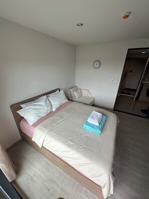 Ein Schlafzimmer mit einem Bett, Kissen, einer Uhr und einer Tür zu einem Badezimmer.