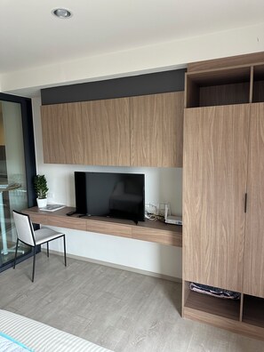 Eine moderne Küche mit integriertem Fernseher, Holzschränken und einem Essbereich mit Glastisch und Stuhl.