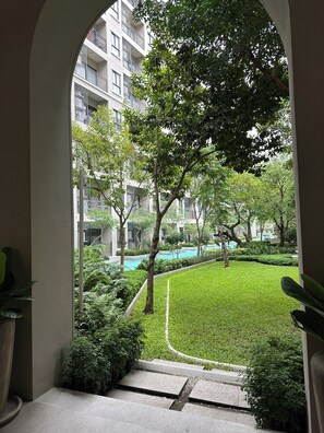 Um pátio com piscina, rodeado por vegetação e edifícios altos.