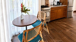 Eine moderne Küche mit Holzschränken, einem Edelstahlkühlschrank und einem Essbereich mit rundem Tisch und Stühlen.