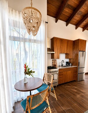 Una cocina moderna con armarios de madera, un refrigerador de acero inoxidable y un comedor con una mesa redonda y sillas.