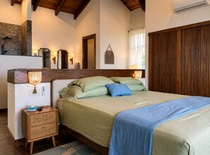 Un dormitorio con cama, mesita de noche y cabecero de madera.
