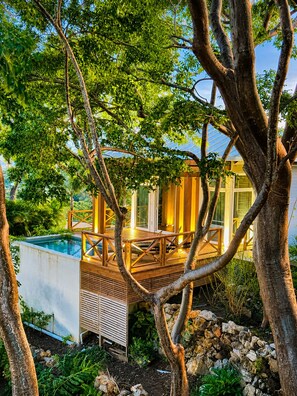 Un área junto a la piscina con cubierta de madera, piscina y un edificio con amplios ventanales.