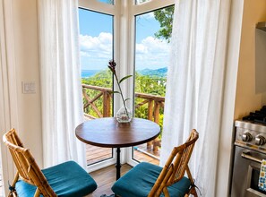 Un balcon avec une table et des chaises, une vue sur la verdure et un réchaud.
