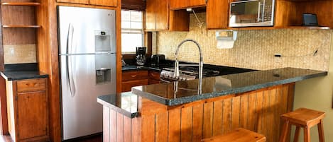 Una cucina con mobili in legno, un frigorifero in acciaio inossidabile, un forno a microonde e un lavandino.