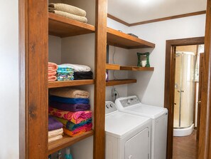 Un espace buanderie avec un lave-linge et des piles de serviettes rangées sur des étagères.