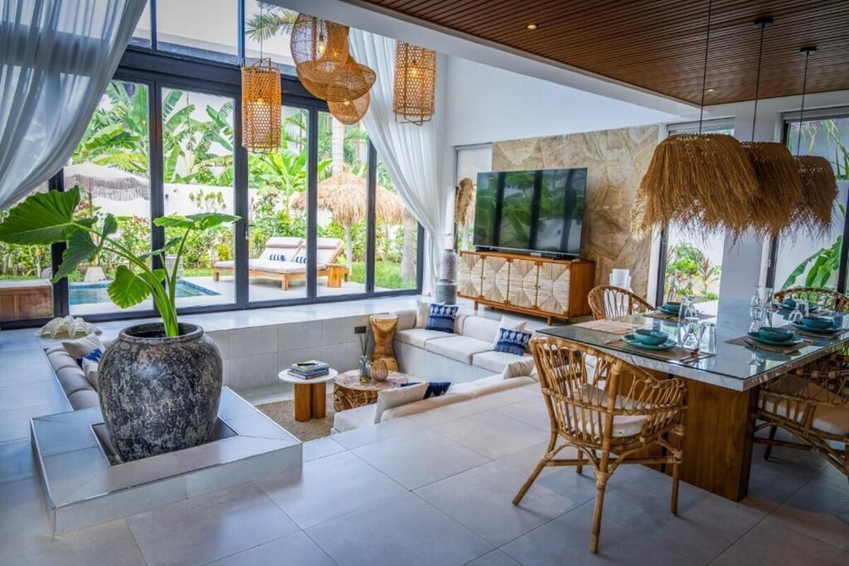 A modern living room with a large TV, comfortable seating, and a dining area with a table set for four.