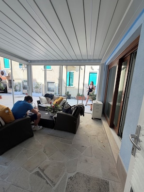 A covered patio area with wicker furniture, a stone floor, and a view of the street. - Chioggia: Between the Sea, History, and Tradition (Chioggia)