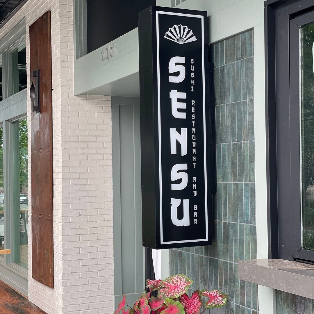 A black sign with white lettering for a sushi restaurant named SENSU.
