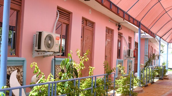 A pink building with air conditioning units, a balcony, and a railing.