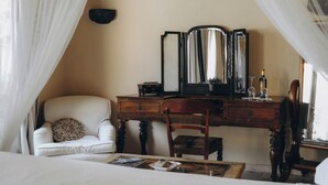 Ein Schlafzimmer mit einem Bett, einem hölzernen Schminktisch, einem Stuhl und einem Spiegel.