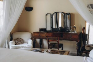 A bedroom with a bed, a wooden dresser, a chair, and a mirror. - Cortijo El Aguilón, a hidden paradise in Tarifa. (Tarifa)