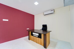 A reception desk with a sign, a black office chair, and an air conditioning unit on the wall.