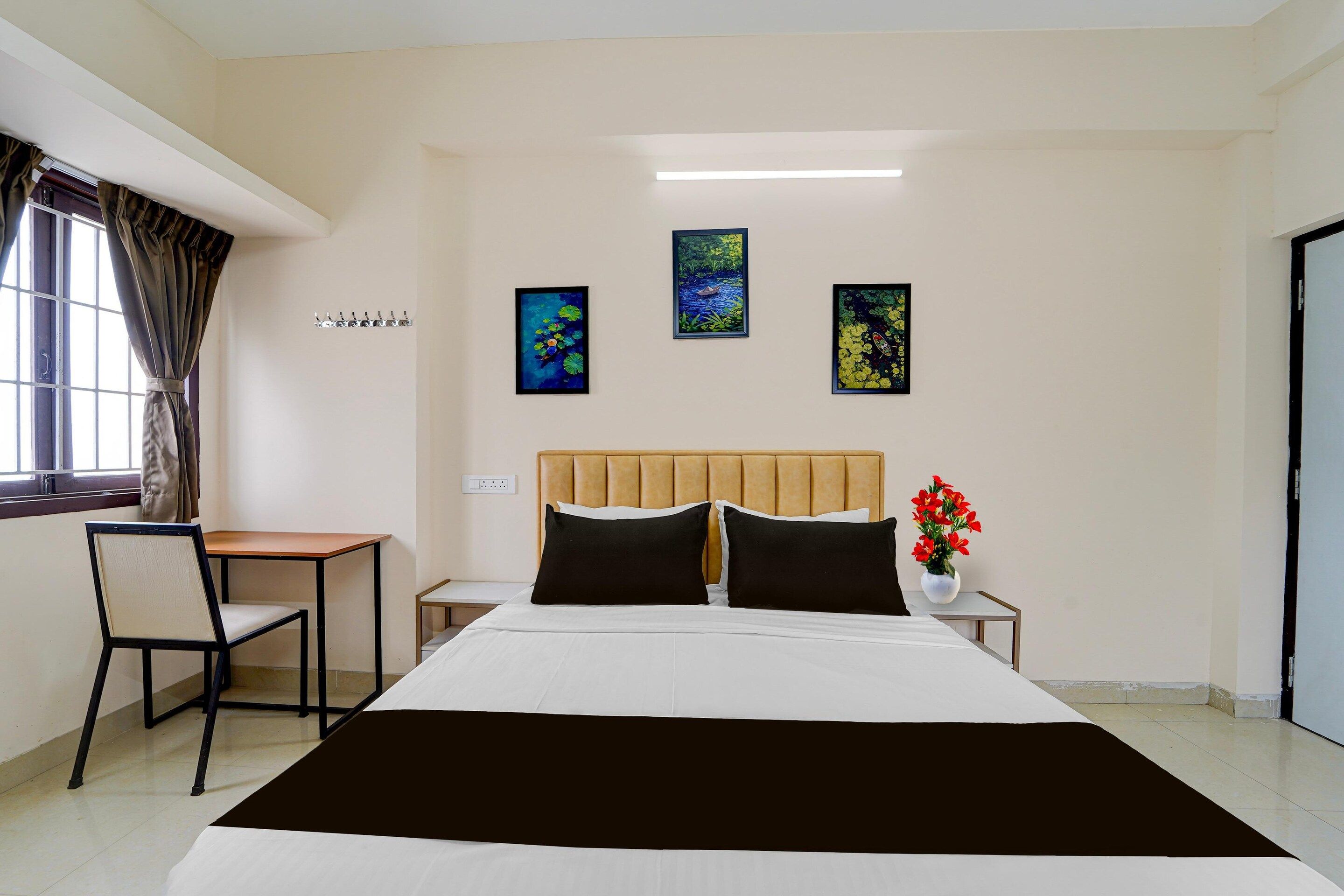 A hotel room with a bed, a desk, a chair, and artwork on the walls.