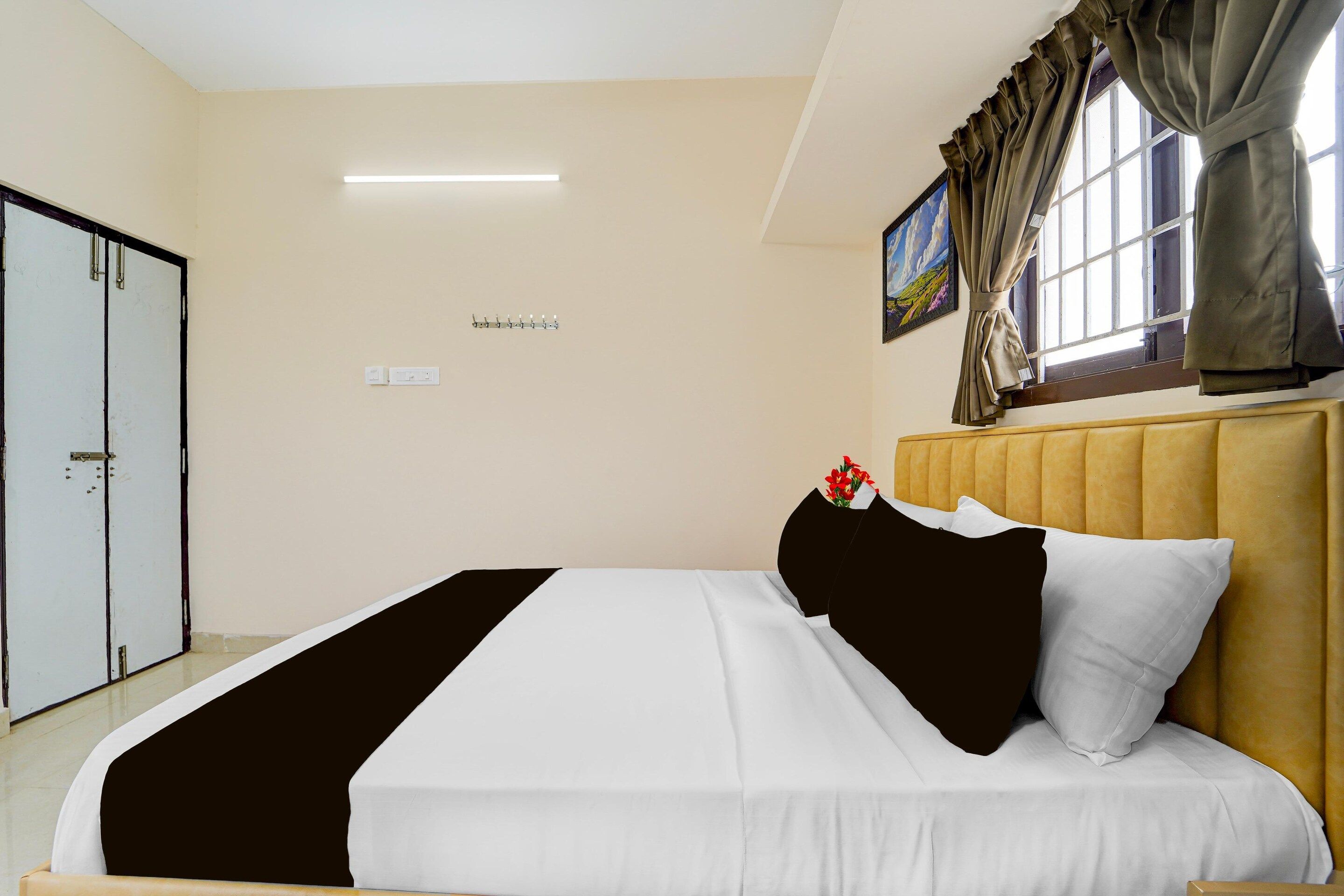 A hotel room with a bed, a wardrobe, a painting, and a window with curtains.