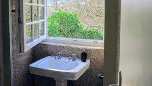 Une salle de bain avec une fenêtre, un lavabo et une porte.