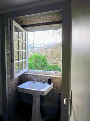 Ein Badezimmer mit Fenster, Waschbecken und Tür.