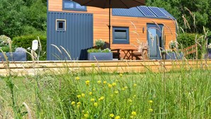 A modern, compact cabin with a large umbrella, solar panels, and a small deck. - Tiny House Prum - Natururlaub in der Eifel (Pruem)