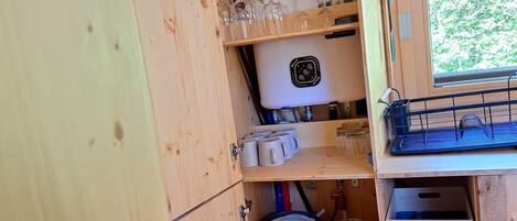 Une cuisine compacte dotée de meubles en bois, d’un téléviseur à écran plat et de divers ustensiles de cuisine.