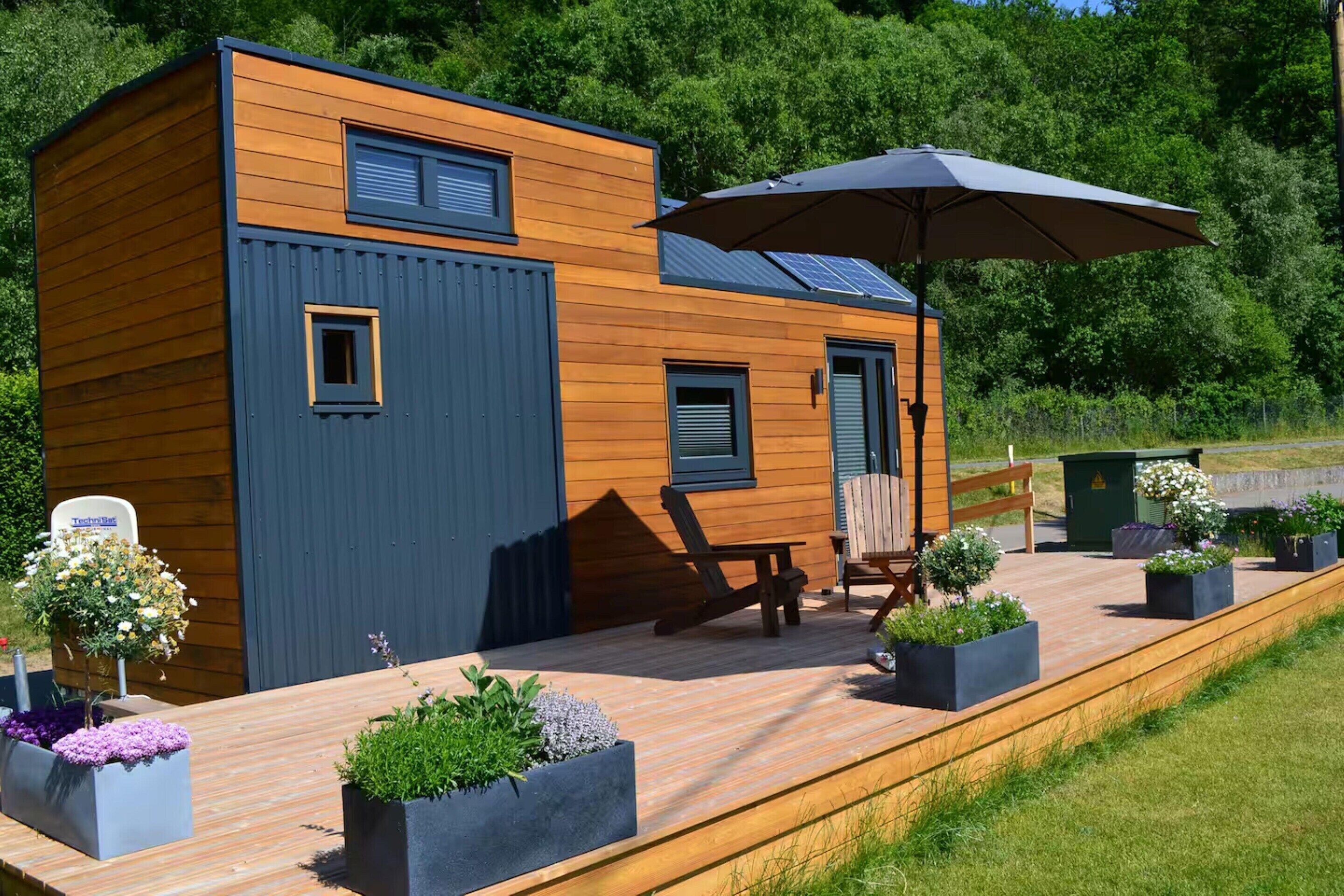 Une cabane moderne en bois, dotée d’une terrasse, d’un espace salon extérieur et de jardinières.