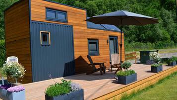 Une cabane moderne en bois, dotée d’une terrasse, d’un espace salon extérieur et de jardinières.