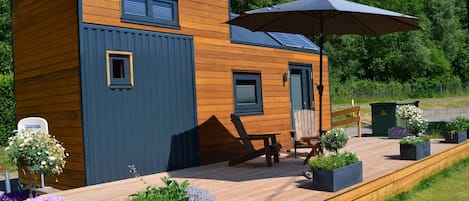 Une cabane moderne en bois, dotée d’une terrasse, d’un espace salon extérieur et de jardinières.
