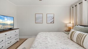 A bedroom with a bed, a TV, a dresser, two framed pictures, and a lamp. - Bradley Beach Compound:2 homes, sleeps 11,+parking (Bradley Beach)