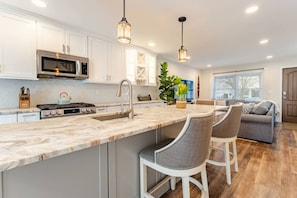 A modern kitchen with a central island, stainless steel appliances, and pendant lighting. - Bradley Beach Compound:2 homes, sleeps 11,+parking (Bradley Beach)