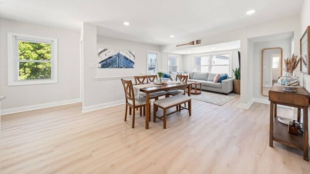 A spacious living area with a dining table, sofa, and large windows. - Bradley Beach Compound:2 homes, sleeps 11,+parking (Bradley Beach)