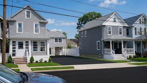 A residential street with two houses, a driveway, and a parked car. - Bradley Beach Compound:2 homes, sleeps 11,+parking (Bradley Beach)