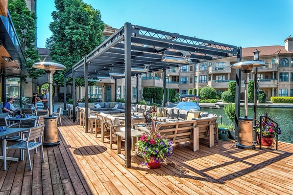 Une terrasse en bois avec des sièges extérieurs, un espace abrité et une vue sur un plan d’eau.