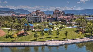 Un hotel junto al lago con un patio central, piscina y vistas a las montañas al fondo.