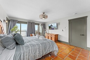 A hotel room with a bed, a wooden dresser, a television, and a door.