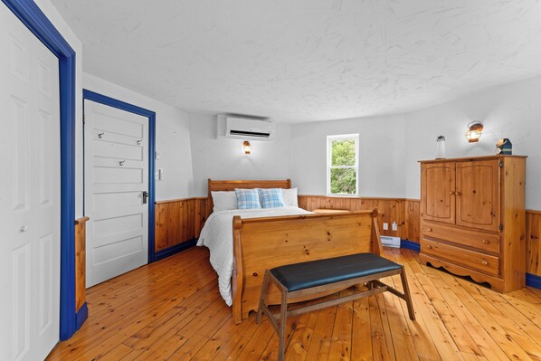 A bedroom with a wooden bed, a bench, a wardrobe, and a window.