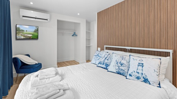 Un dormitorio moderno con cama, televisor, armario y baño.
