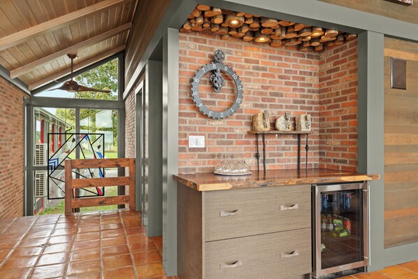 A kitchen with a brick wall, a wooden ceiling, and a stainless steel refrigerator.