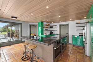 A modern kitchen with a large island, built-in appliances, and a patio area with outdoor seating.