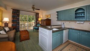 Una cocina con armarios color turquesa, una isla central con pileta y una zona de comedor con mesa y sillas.