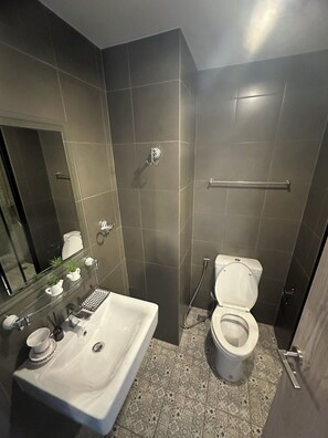 Un baño moderno con un lavamanos blanco, un inodoro y una zona de ducha.