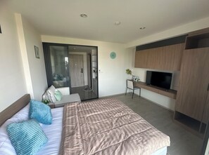 Ein modernes Hotelzimmer mit Bett, Schreibtisch, Fernseher und Kleiderschrank.