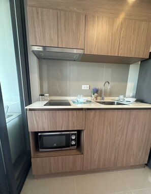 Eine moderne Küche mit Holzschränken, integriertem Mikrowellenherd, einer Edelstahlspüle und einer Dunstabzugshaube.
