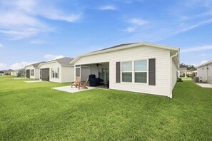 A single-story residential building with a covered patio area, a lawn, and a clear sky. - Dog-Friendly Coastal Cottage | Golf Cart (Sumterville)