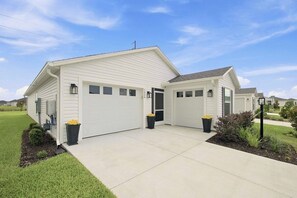 Une maison de plain-pied avec un garage, un porche à l’avant et une pelouse bien entretenue.