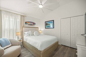 Une chambre à coucher comprenant un lit, une chaise, un ventilateur de plafond et une armoire.