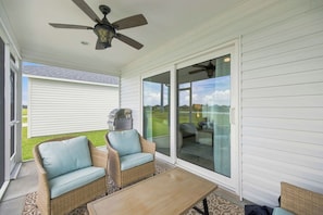 A covered patio area with wicker furniture, a ceiling fan, and a view of the backyard. - Dog-Friendly Coastal Cottage | Golf Cart (Sumterville)