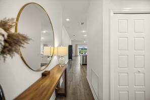 A hallway with a wooden console table, a mirror, and a white door. - Dog-Friendly Coastal Cottage | Golf Cart (Sumterville)