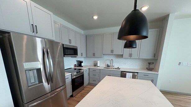 A modern kitchen with stainless steel appliances, white cabinetry, and a marble countertop. - 3-bedroom Luxury townhome in brilliant Edmond 5 min to UCO (Edmond)