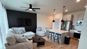 A modern kitchen with a central island, bar stools, and a ceiling fan. - 3-bedroom Luxury townhome in brilliant Edmond 5 min to UCO (Edmond)